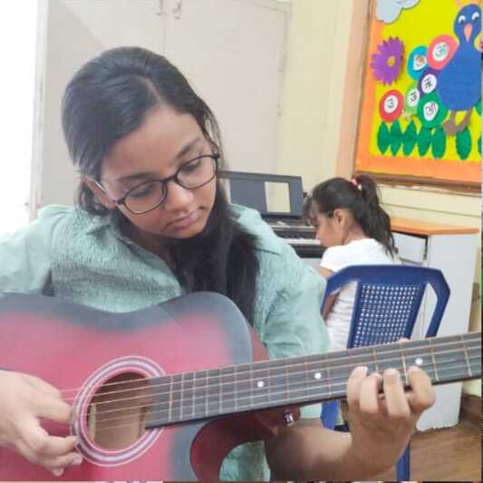 Student learning guitar chords at Natraj Sangeet Center